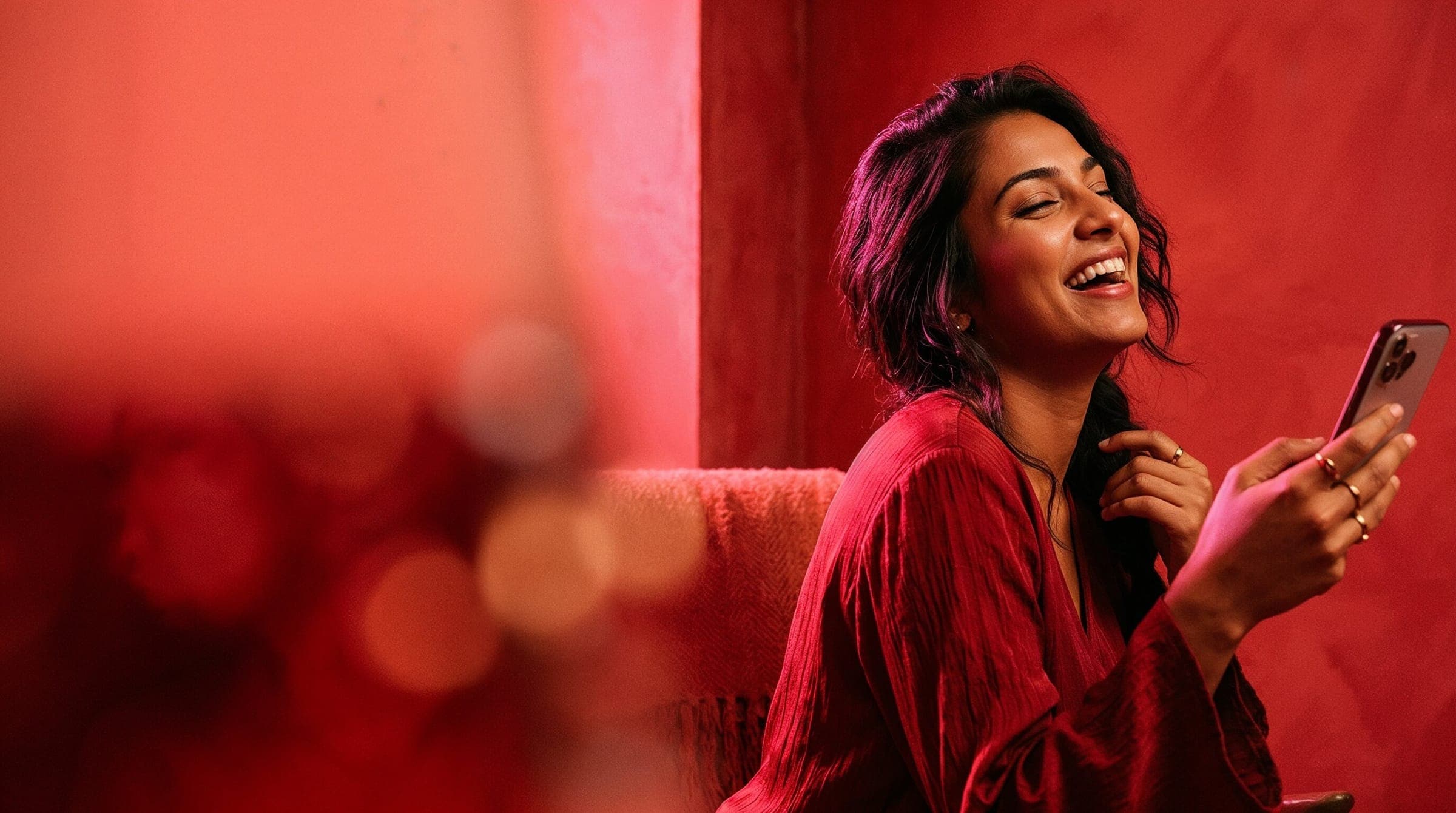 A creator laughing joyfully holding her phone in a coral-lit room